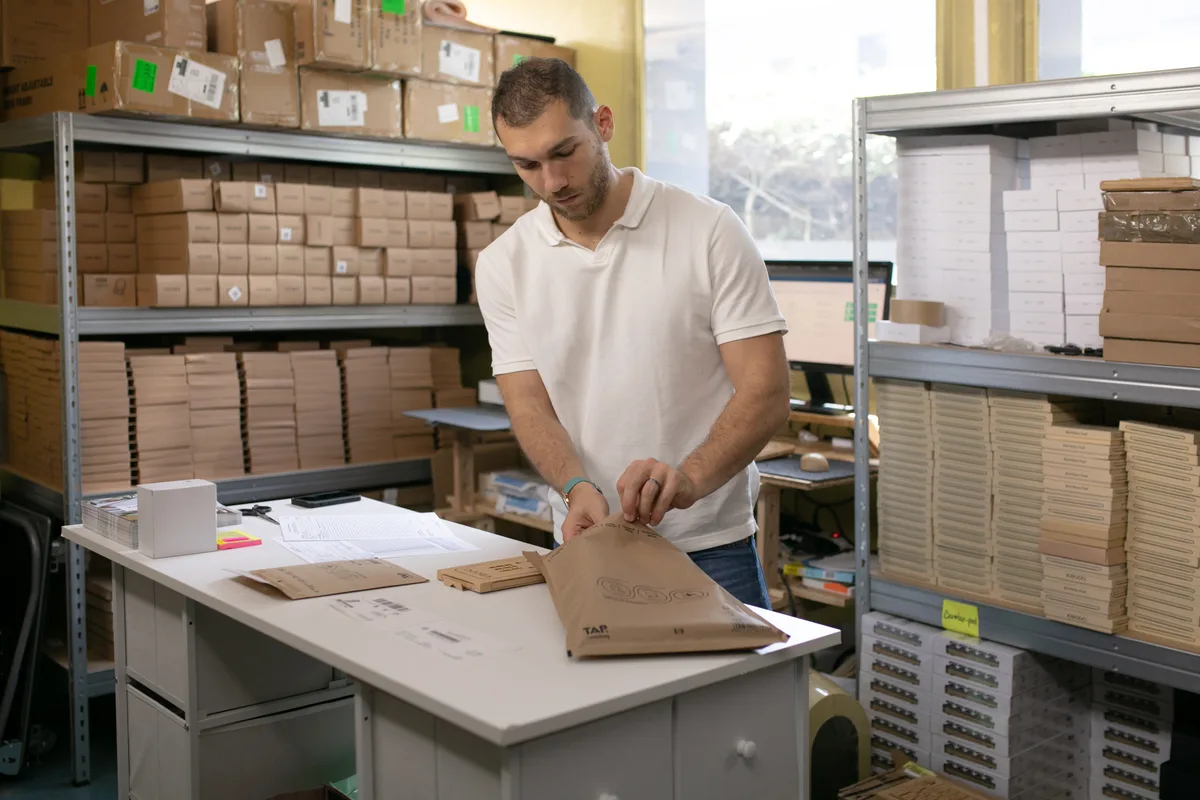 Florian Chaloupy prépare une commande dans son espace de stockage à Hélioparc, entre les étagères de produits et la table d’emballage.